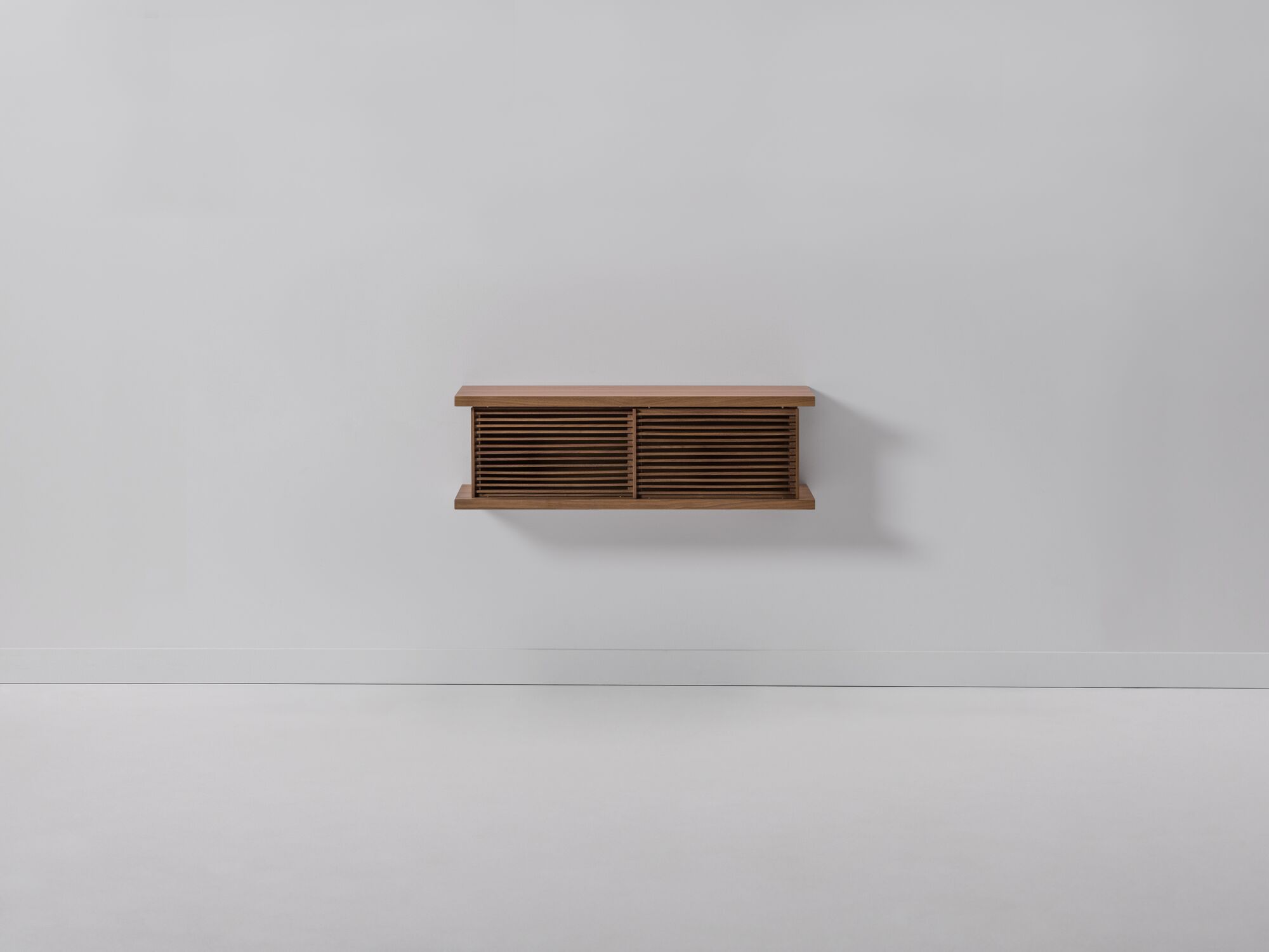 Front view of small walnut floating media unit with slatted doors